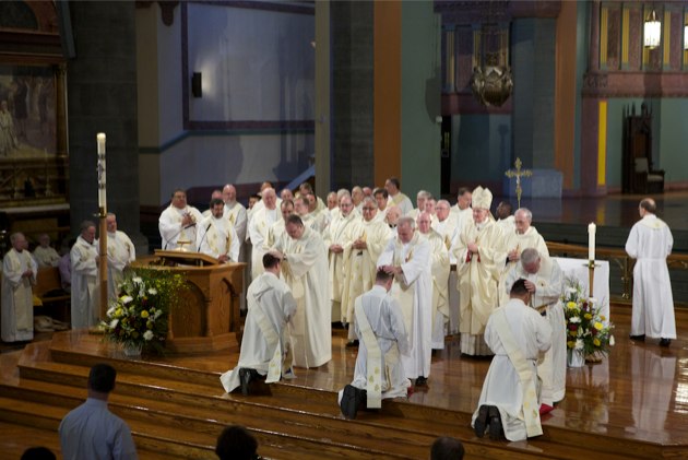 Rev. Mr. Richard R. Andre, CSP, Rev. Mr. Thomas C. Gibbons, CSP, and Rev. Mr. Rene I. Constanza, CSP, kneel in front of the altar as thier Paulist brothers lay hands on their heads as a sign of welcome into the Paulist priesthood. (Photo: BruceByers.com)